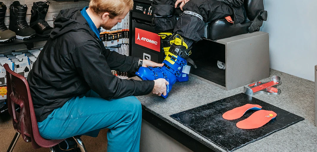 Ski boot fitting process with a technician adjusting the fit for a customer